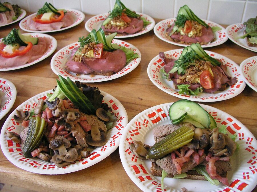 Several smørrebrød on dark rye spread across a table at a Copenhagen lunch