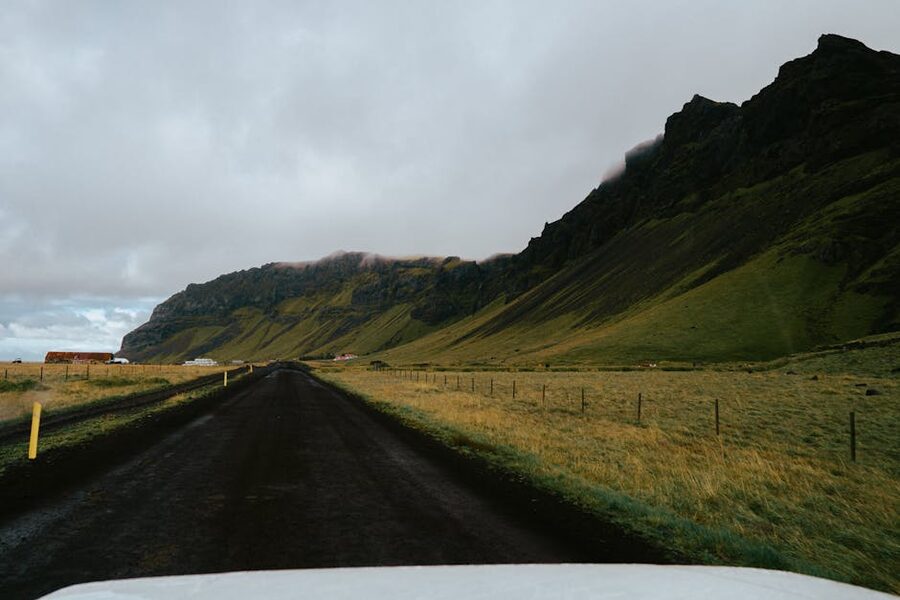 Empty road through green Icelandic mountains under cloud