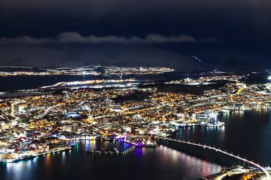 Tromsø city lights at night with a hint of aurora over the harbour