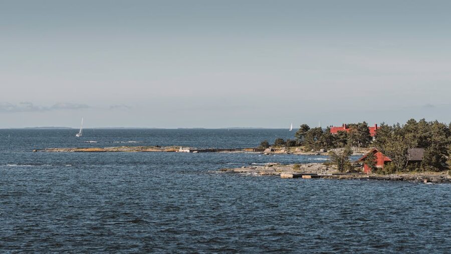 Sailboats and traditional red Finnish wooden houses on a rocky archipelago shore