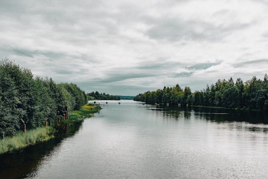 A calm river with green trees and a clouded sky over the Aurajoki