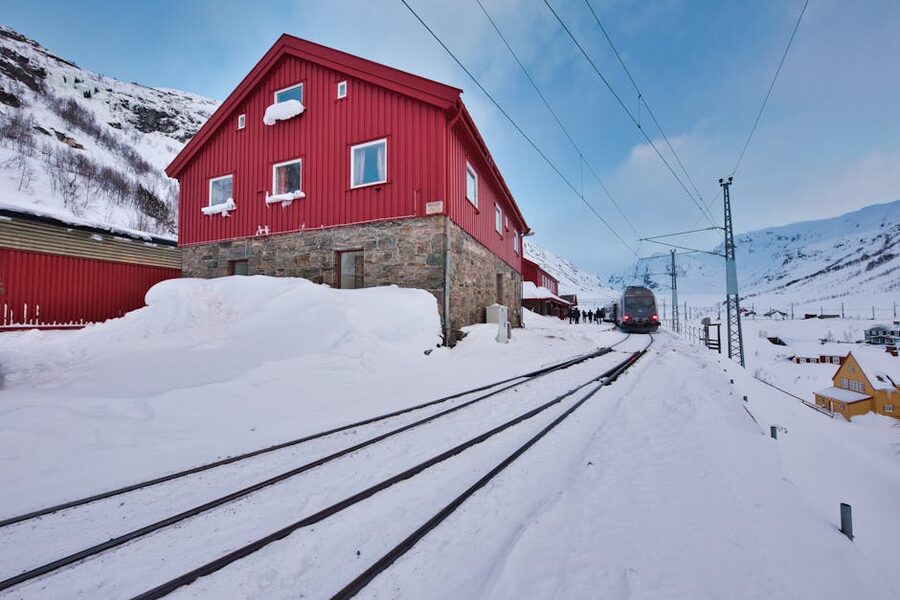 Red Norwegian wooden house and railway tracks in deep snow